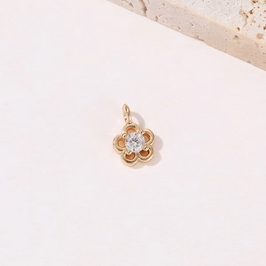 Minimalistischer goldener Blumenanhänger mit glänzendem Zirkonia auf Textur