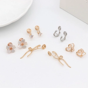 Variety of gold-plated cherry blossom and heart non-pierced clip-on earrings on white tray