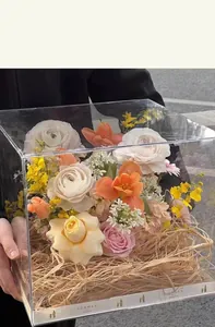 Clear acrylic gift box with natural raffia filler and colorful mixed spring flower bouquet