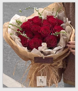 Natural raffia ribbon tie on red rose bouquet wrapped in vintage brown kraft paper