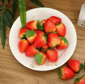 Close-up of artificial strawberries in a decorative white ceramic plate on wooden table