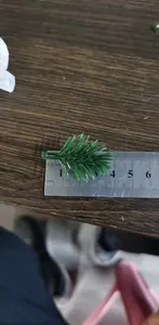 Detailed view of artificial Christmas pine needles with ruler for size reference