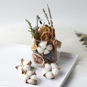 Natural dried cotton flowers and cinnamon sticks in a glass jar with leather handle
