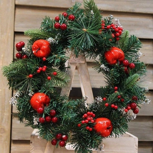 Christmas wreath with artificial red berries and pine needles on a rustic wooden ladder