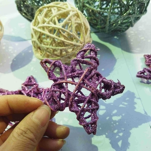 Detail of hand holding a 6cm purple glitter rattan star for Christmas decorations