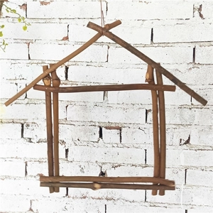 Handmade house-shaped wood branch frame for air plants hanging on white brick wall