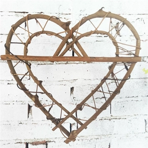Natural woven rattan heart wreath decor with central wooden bar on a white brick wall