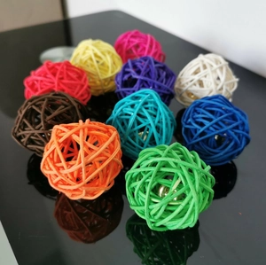 Set of ten colorful wicker rattan balls with bells for cats on reflective black surface