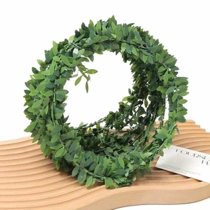 Artificial green leaf garland handcrafted with realistic plastic leaves on a wooden tray
