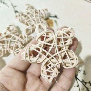 Close-up of hand holding natural cream-colored rattan stars for bird foot toys