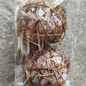 Close-up of bird parrot chewing toy made of woven rattan balls in plastic packaging