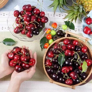 Realistic artificial cherries with green leaves in a basket for home kitchen decor
