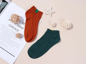 Détail de chaussettes en coton côtelé avec étiquettes tissées et boules de rotin déco