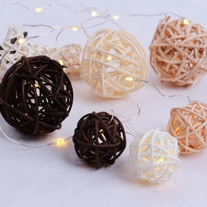 Gros plan de guirlandes lumineuses boules de rotin LED aux tons terreux sur tissu blanc