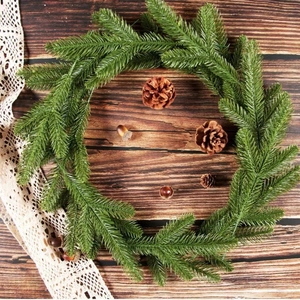 Ghirlanda di pino artificiale verde con pigne su sfondo di legno scuro per Natale