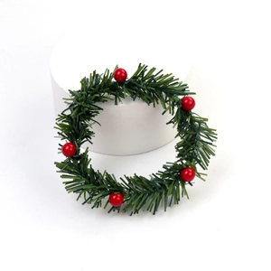 Mini couronne de Noël avec aiguilles de pin vertes et baies rouges sur un socle