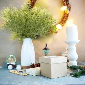 Artificial cypress branches in a ceramic vase with festive Christmas wreath background decor