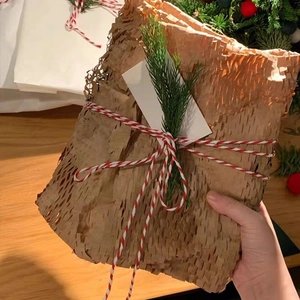 Eco-friendly honeycomb paper gift wrap with red and white twine and a festive pine sprig