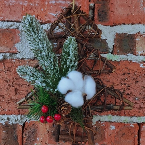 Christmas tree wreath with red berries, pine cones and cotton balls on a red brick wall