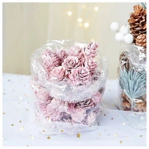 Pommes de pin teintes en rose et baies blanches pour décoration de Noël sur tulle étoilé