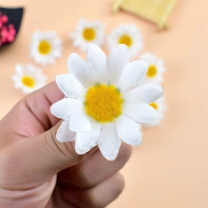 Hand holding a white artificial daisy silk flower for DIY crafts and decor
