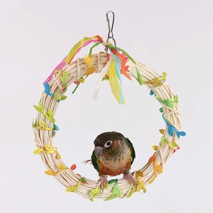 Detail of woven straw bird swing with colorful paper ribbons and metal hanging hook