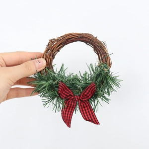 Mini Christmas wreath with buffalo plaid bow and green pine needles on natural rattan vine