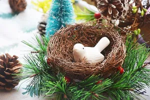 Detail of white ceramic bird figurine nestled in a woven rattan nest base for decoration