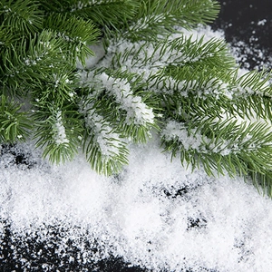 Realistic artificial snow powder on green pine branches for Christmas scene decoration