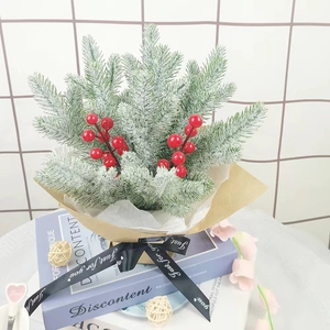 Artificial cedar pine branches with red berries and snow effect in craft paper gift wrap