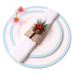Christmas napkin ring with red berries, pine needles, and burlap lace on a white plate