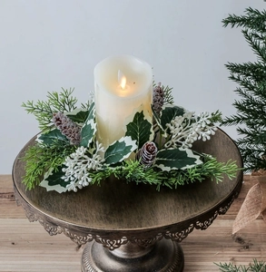 Close-up of LED candle with Christmas wreath of pine needles, cones and white berries
