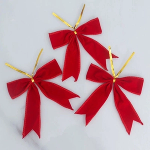 Trois nœuds de Noël en velours rouge avec attaches dorées sur fond marbre pour décor