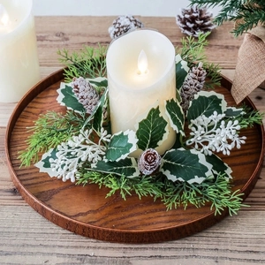Christmas LED candle with red berry wreath and pine cones on a rustic wooden base