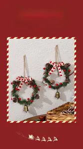 Detail of Christmas wreath with pine cones, red berries, bells and heart bow on white wall