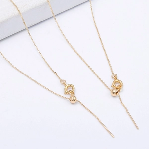 Macro detail of fine gold chain necklace featuring spring clasp and small bead accents