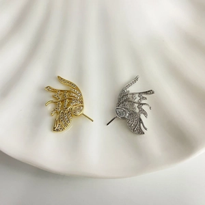 Dettaglio dei ciondoli a forma di ali in oro e argento con zirconi scintillanti