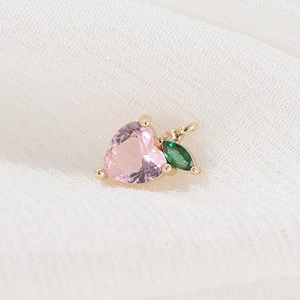 Detailopname van perzik hanger met roze hartvormig kristal en gouden zetting
