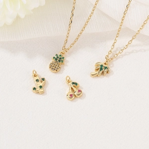 Exquisite gold-plated summer fruit pendants with colorful zircon on a textured fabric background