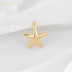 Golden starfish pendant with polished metal finish on a textured white fabric background