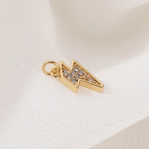 Gold plated lightning bolt pendant with sparkling zircons on white soft tulle fabric