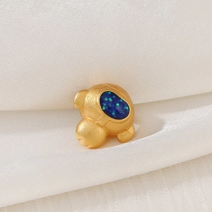 Detail of matte gold astronaut charm with blue starry glitter helmet on white silk