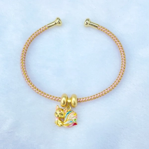 Golden fox pendant bracelet with colorful enamel details on white plush background