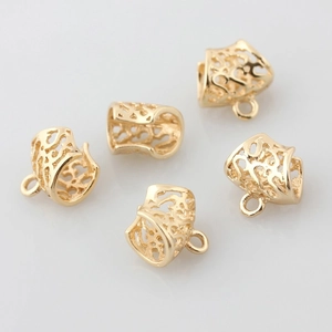 Detailed macro view of five hollow gold-plated filigree barrel charms for DIY jewelry making