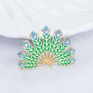 Detail of peacock feather jewelry accessory with gold alloy and green enamel inlay