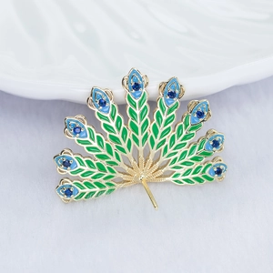 Macro detail of a peacock feather jewelry base with green enamel and blue zircon stones