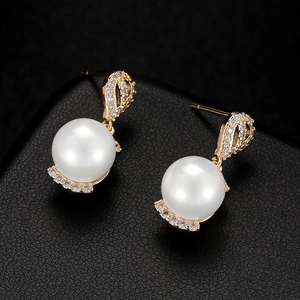 Detailed macro view of 925 silver pearl earrings with gold plating and zircon inlay stones