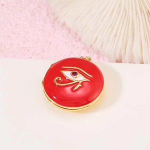 Detalle de medallón redondo de esmalte rojo con ojo de Horus dorado y cristal púrpura