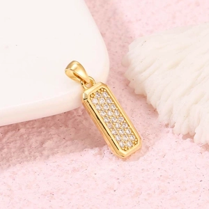 Minimalistischer Goldstab-Anhänger mit 21 eingelegten Zirkonia auf weichem rosa Hintergrund