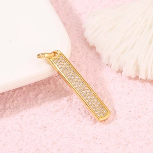 Minimalistischer Goldstab-Anhänger mit Zirkonia-Besatz auf weißem Korallen-Hintergrund